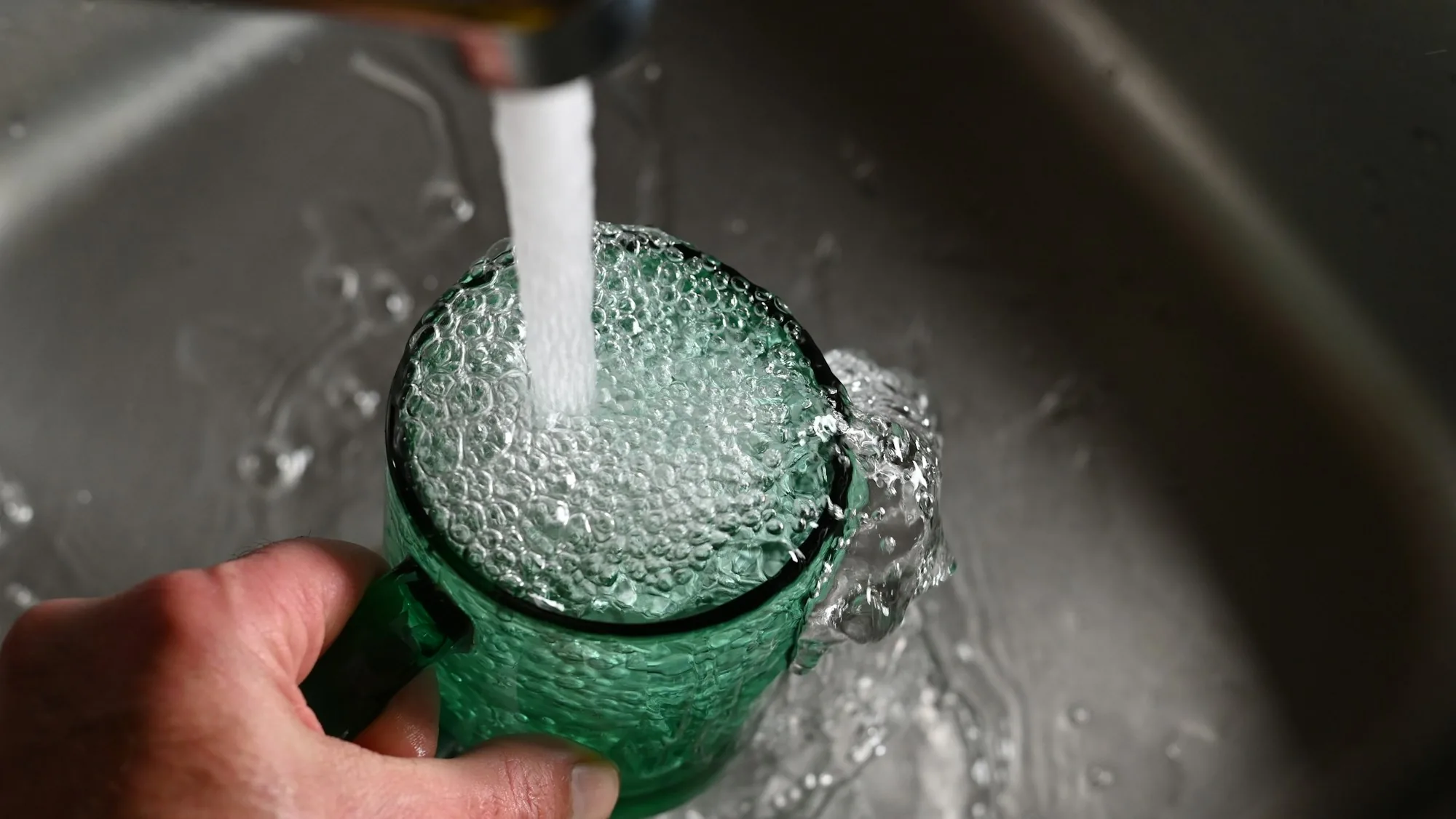 Kitchen faucet running clear water into a glass in a bright home kitchen