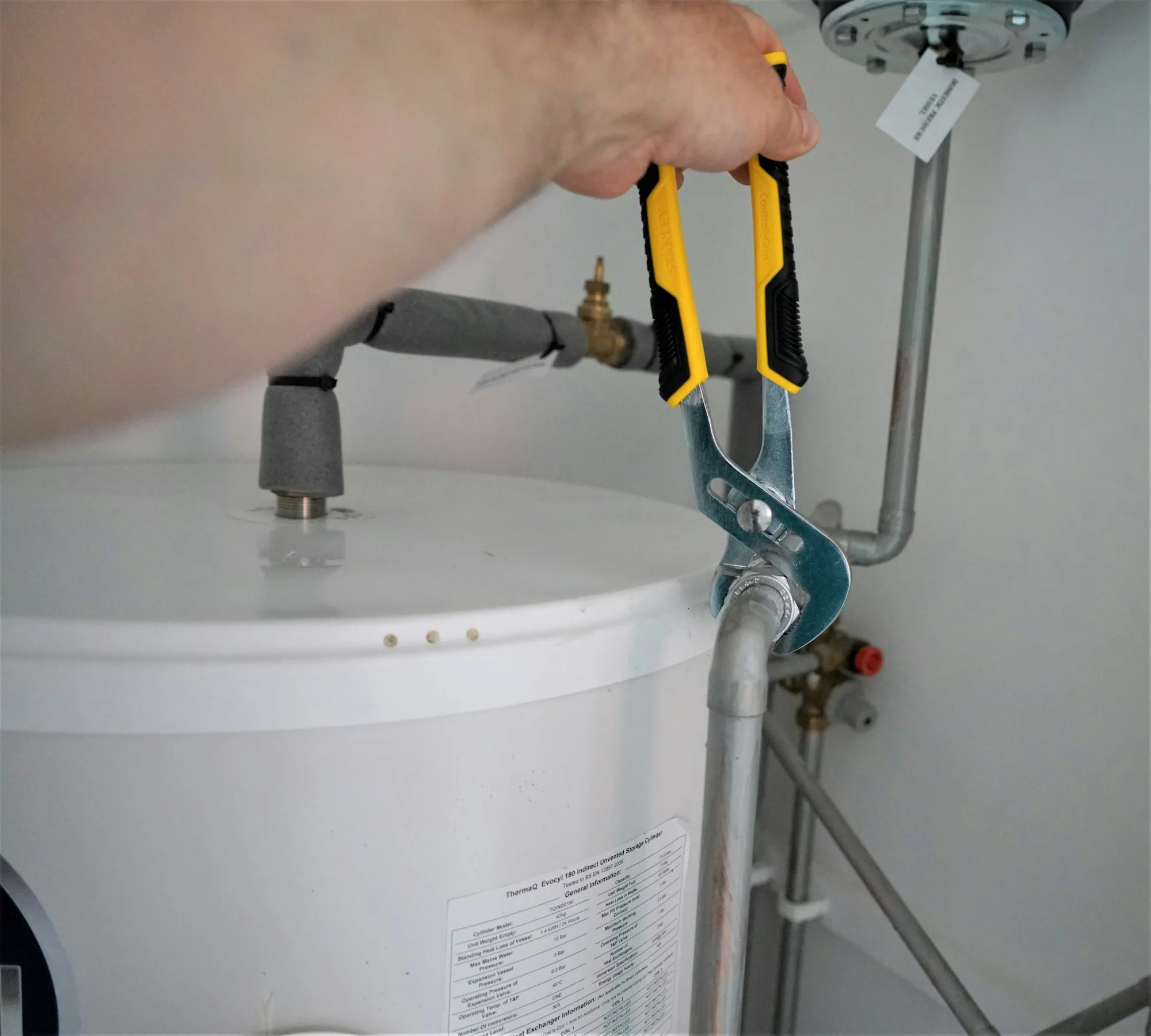 Technician's hands working on a supply valve beside a tank