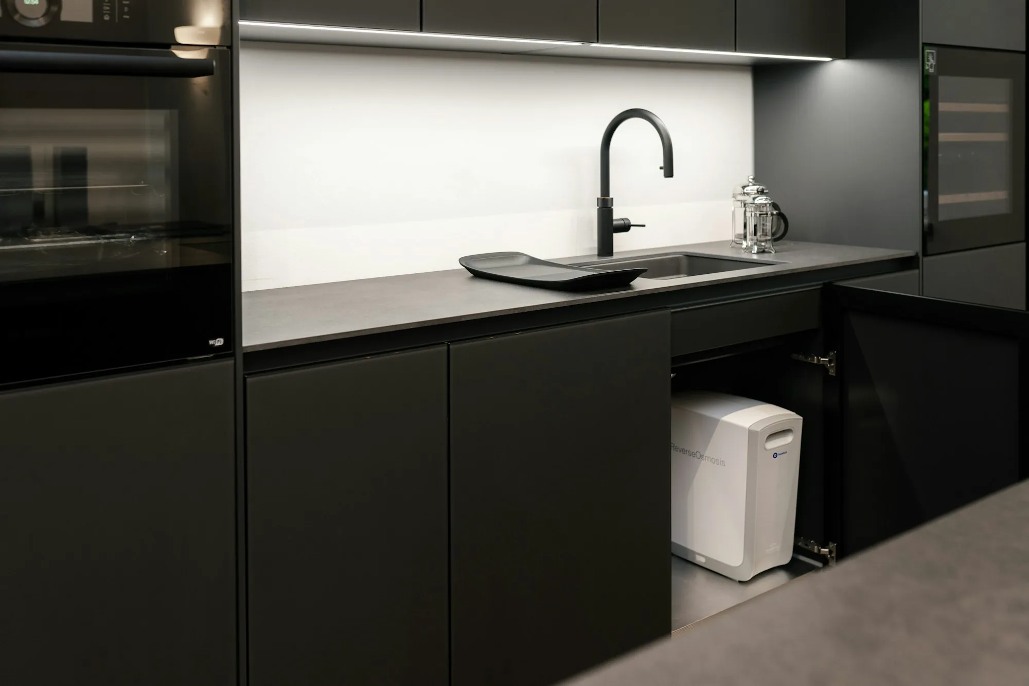 Multi-stage reverse osmosis drinking water system with membrane housing and storage tank mounted in a kitchen cabinet